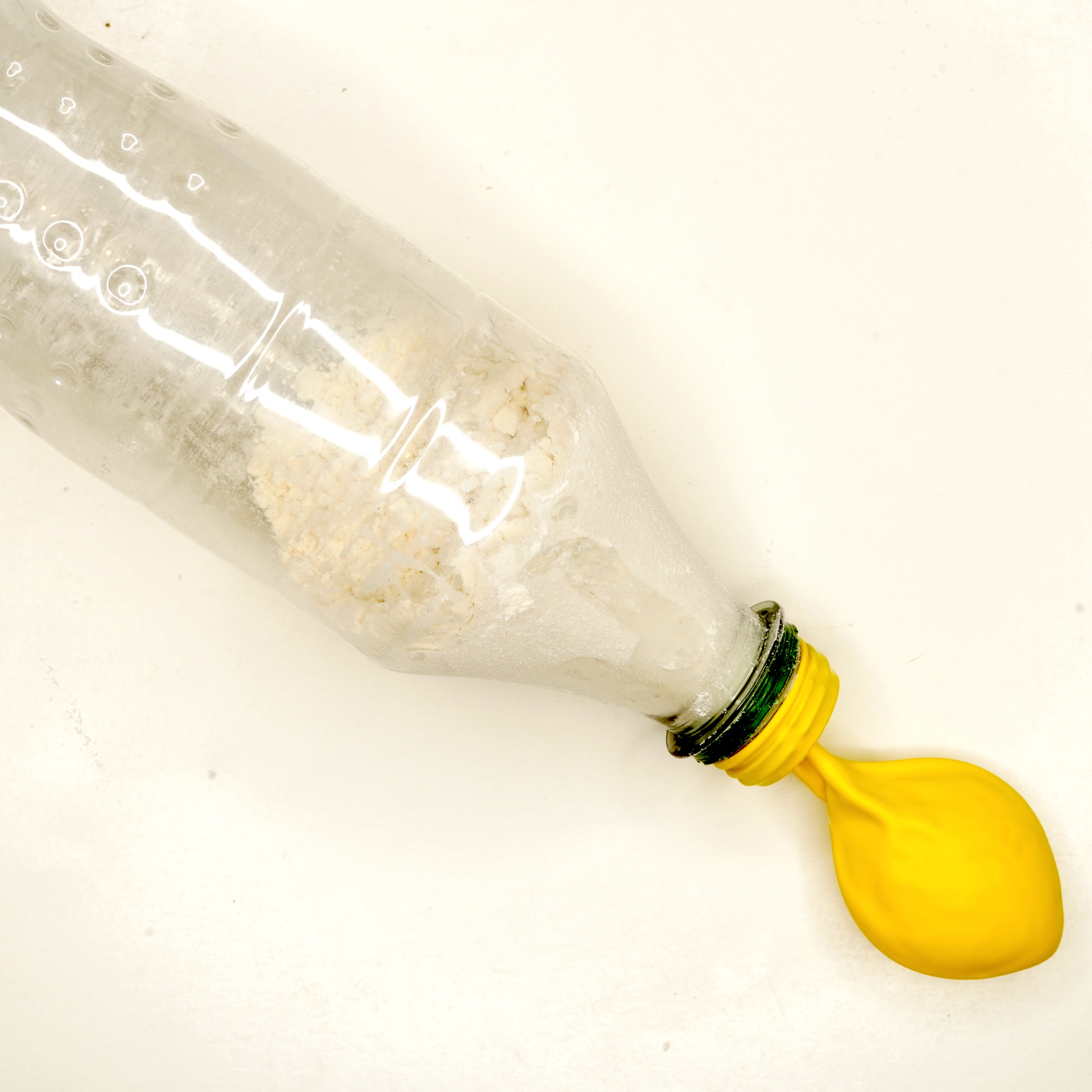 Verser la farine dans la bouteille d’eau puis placer le ballon sur le goulot de la bouteille et retourner la bouteille pour que la farine remplisse le ballon. Faire un noeud au ballon